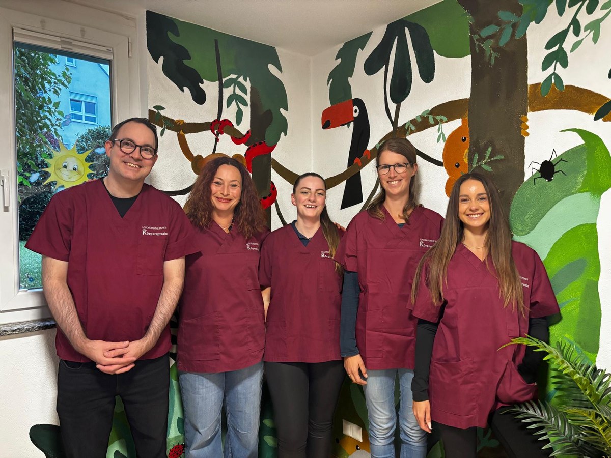 Das fünfköpfige Team der Praxis Körpersprache in bordeauxfarbener Praxiskleidung